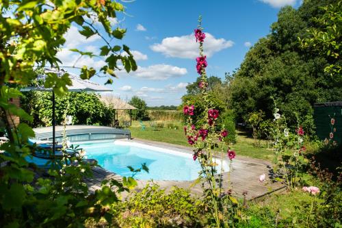 - une piscine dans un jardin fleuri dans l'établissement La Jolie Longère Fleurie Roulotte avec piscine et grand jardin, à Le Gué-dʼAlléré
