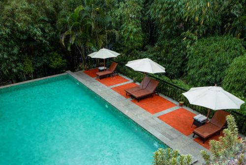 a swimming pool with two chairs and umbrellas at The Hive, Wayanad in Wayanad