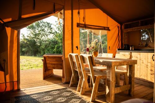 a wooden table and chairs in a tent at La Jolie Longère Fleurie Lodge avec piscine et jardin in Le Gué-dʼAlléré