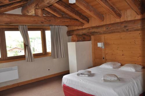 une chambre avec un lit dans une pièce avec des plafonds en bois dans l'établissement Cortina - 51 - Appart spacieux - 10 pers, à Les Deux Alpes