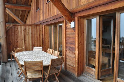 - une table à manger et des chaises sur une terrasse couverte dotée de murs en bois dans l'établissement Cortina - 51 - Appart spacieux - 10 pers, à Les Deux Alpes