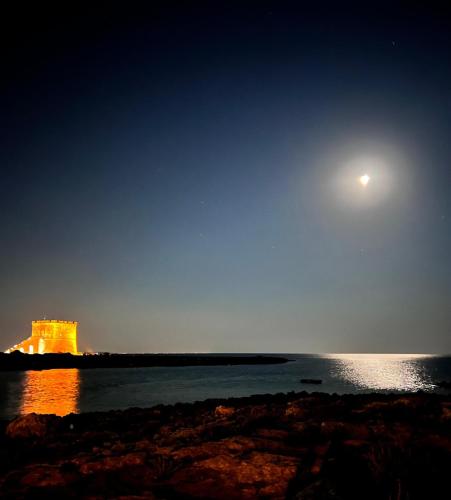 a full moon over the water with a castle in the background at La Dimora del Salento in Torre Lapillo