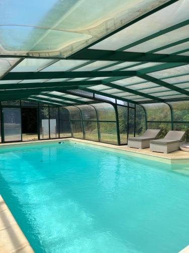 une grande piscine avec de l'eau bleue dans un immeuble dans l'établissement Le Clos du Cèdre, à Saint-Ouen