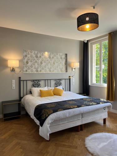 une chambre avec un grand lit avec des oreillers jaunes dans l'établissement Le Clos du Cèdre, à Saint-Ouen