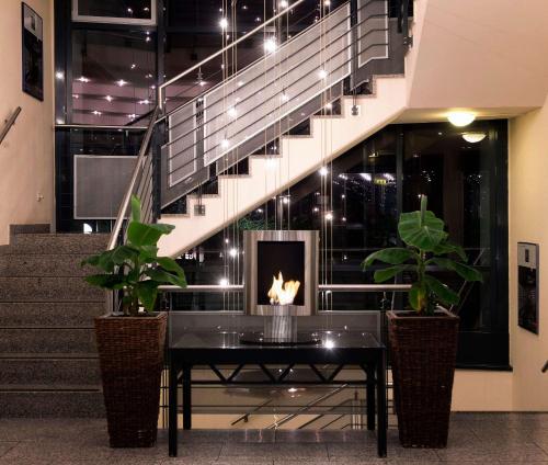a table with a fireplace in a lobby with stairs at Wyndham Garden Hennigsdorf Berlin in Hennigsdorf