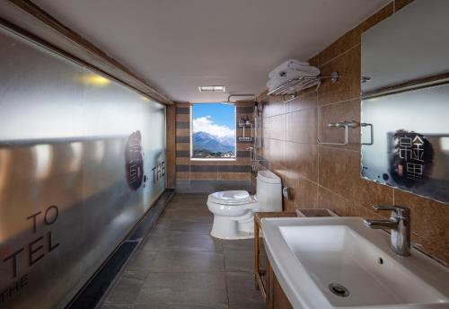 a bathroom with a toilet and a sink with a window at Jinli Chinese Courtyard Inn in Lijiang