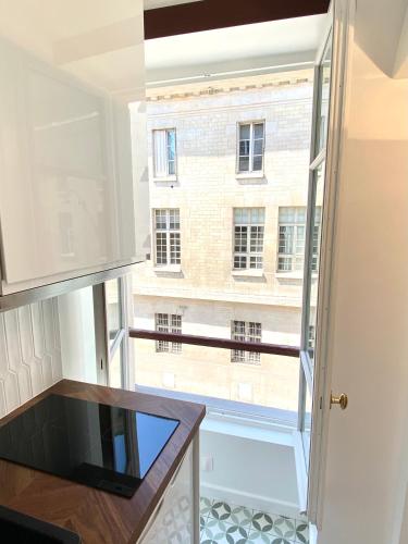 une cuisine avec une grande fenêtre et une table dans l'établissement Brand New Apartment - Rue Cler Paris, à Paris