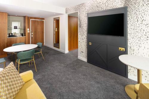 a hotel room with a tv and tables and chairs at DoubleTree by Hilton Leeds in Leeds