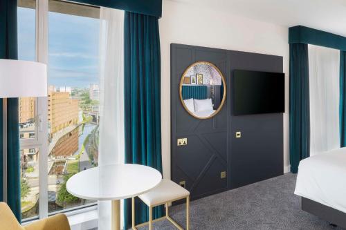 a hotel room with a bed and a table and a mirror at DoubleTree by Hilton Leeds in Leeds