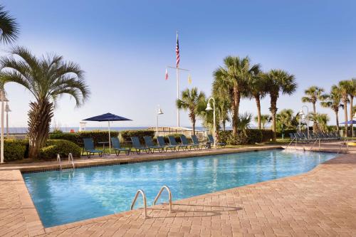 a large swimming pool with chairs and palm trees at Hampton Inn & Suites Myrtle Beach Oceanfront in Myrtle Beach