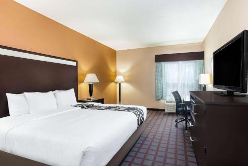 a hotel room with a bed and a flat screen tv at La Quinta by Wyndham Indianapolis Airport Plainfield in Plainfield