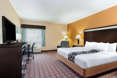 a hotel room with a bed and a flat screen tv at La Quinta by Wyndham Indianapolis Airport Plainfield in Plainfield