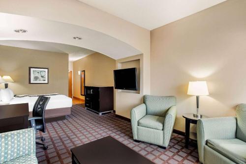 a hotel room with a bed and chairs and a tv at La Quinta by Wyndham Indianapolis Airport Plainfield in Plainfield