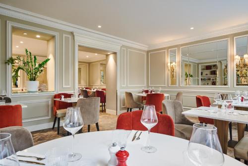 un restaurant avec des tables blanches et des chaises rouges dans l'établissement Hotel Westminster, à Paris