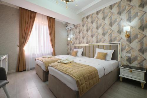 a bedroom with two beds and a stone wall at Hotel Samaria Terrace in Samarkand