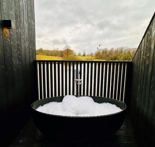 a bath tub filled with snow in front of a fence at Leeds Castle Lakeside Lodges in Broomfield