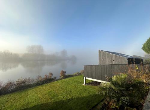 a building on a hill next to a body of water at Leeds Castle Lakeside Lodges in Broomfield