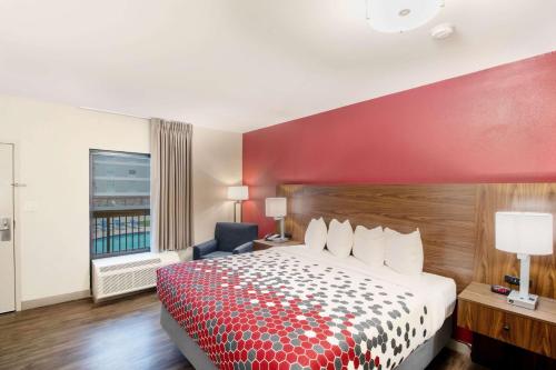 a hotel room with a bed and a red wall at Econo Lodge Inn & Suites Foley-North Gulf Shores in Foley
