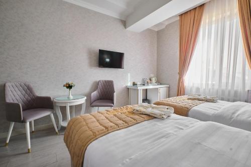 a hotel room with two beds and a tv at Hotel Samaria Terrace in Samarkand