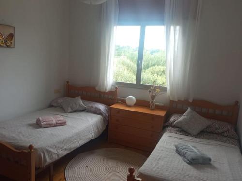 two twin beds in a room with a window at Acogedora casita de campo in Bóveda