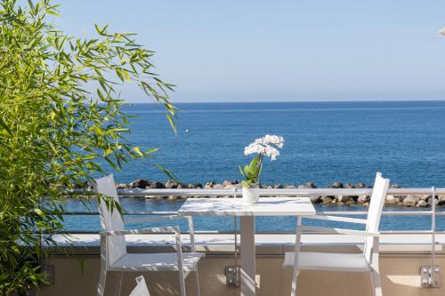 a table and chairs with the ocean in the background at Gli Scogli Luxury Residence Hotel in Chiavari