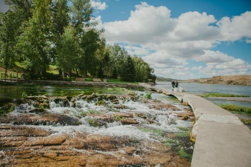 a person walking a dog on a path next to a river at Staybridge Suites Great Falls by IHG in Great Falls