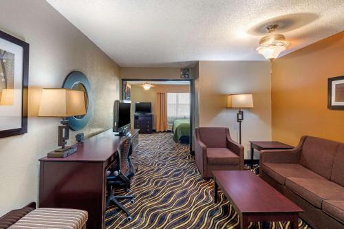 a hotel room with a waiting area with a couch and a bed at Quality Suites Addison-Dallas in Addison