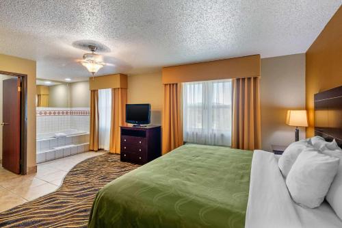 a hotel room with a bed and a television at Quality Suites Addison-Dallas in Addison