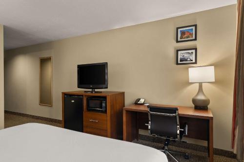 a hotel room with a bed and a desk with a television at Comfort Inn Ogden near Event Center in Ogden