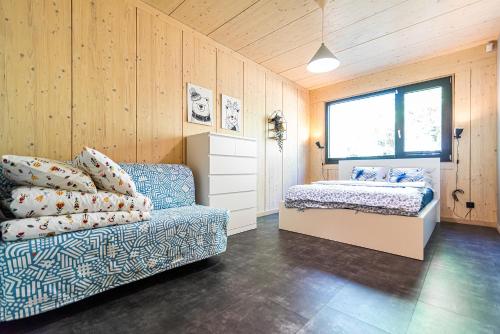 a bedroom with a couch and a bed and a window at Szklany Dom nad Łąkami in Zbiczno