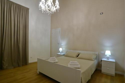 una camera da letto bianca con un letto e un lampadario di Clemente House Catania Centro MERAVIGLIOSA camera matrimoniale a Catania