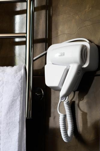 a white hair dryer hanging on a wall in a bathroom at Готельно-ресторанний комплекс Традиція in Pistyn