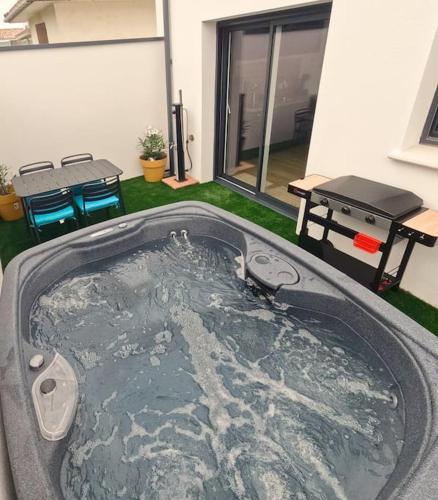 a hot tub in the middle of a yard with a grill at Cocon indépendant avec SPA in La Jarrie