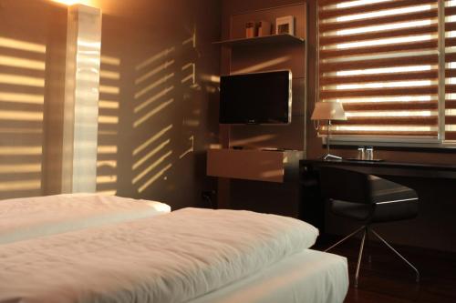 a bedroom with a bed and a desk and a television at Hotel Rosenmeer in Mönchengladbach