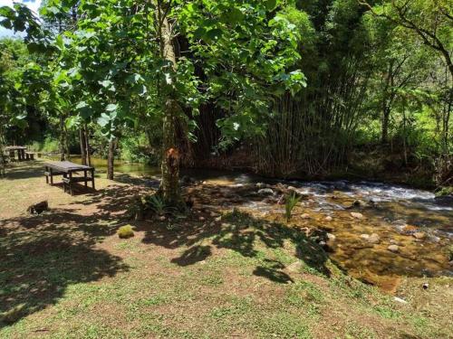 a picnic table sitting next to a stream of water at Chácara Brisa do Rio 2 in Núcleo Colonial