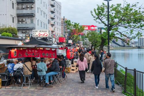 a crowd of people walking down a sidewalk near a river at WeBase Hakata Hostel in Fukuoka