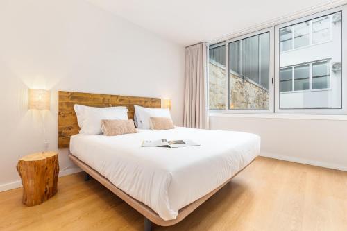 a white bedroom with a large bed and a window at Dream On - Clérigos Lofts in Porto