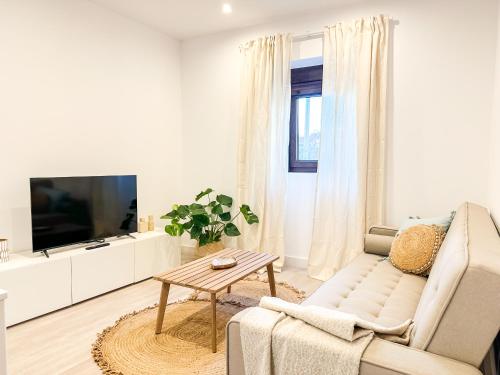 uma sala de estar branca com um sofá e uma TV em A Casa de Canosiña by ALÔGA em Fisterra
