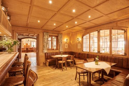a restaurant with wooden walls and tables and chairs at Hotel Auf der Gsteig GmbH in Lechbruck