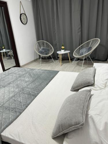 a bedroom with a bed with two chairs and a clock at Oly Apartment in Năvodari
