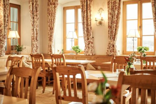 a dining room with tables and chairs and windows at Hotel Auf der Gsteig GmbH in Lechbruck