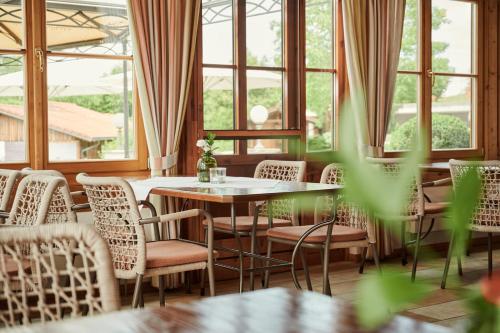 a dining room with tables and chairs and windows at Hotel Auf der Gsteig GmbH in Lechbruck