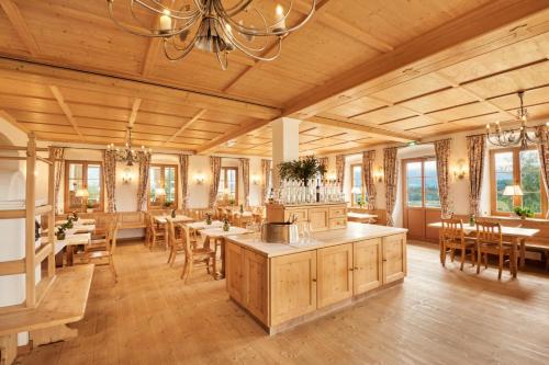a dining room with tables and chairs and a chandelier at Hotel Auf der Gsteig GmbH in Lechbruck