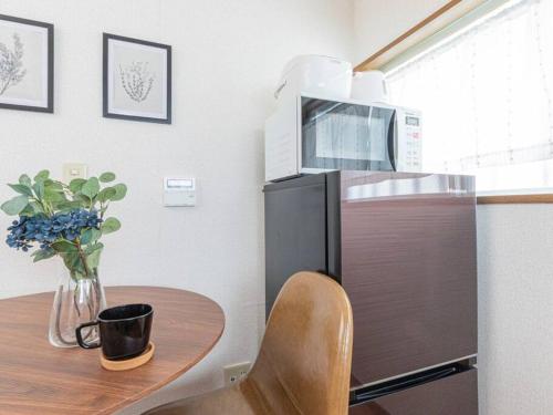 a kitchen with a table with a microwave on top of a refrigerator at Discover Tokyo's soul Your cozy Japanese escape! in Tokyo