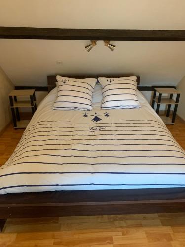 - un lit avec des draps rayés et des oreillers dans l'établissement Gîte de la Guinchère Bretagne, à Saint-Georges-de-Reintembault