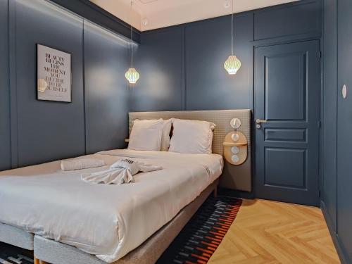 a bedroom with a bed with blue walls and pendant lights at Aparthotel AMMI Nice Lafayette in Nice