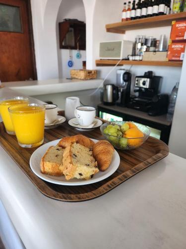 a tray with a loaf of bread and a bowl of fruit at Hotel Kastelakia Mykonos in Mýkonos City