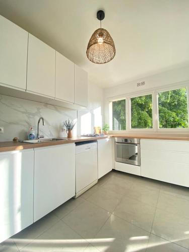 une cuisine avec des placards blancs et une lampe pendant dans l'établissement Grand appartement 6 personnes à 5min de Versailles avec parking privé, à Le Chesnay