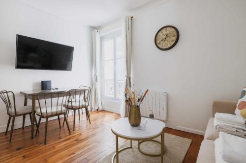 - un salon avec une table et une horloge murale dans l'établissement Cosy and chic apartment -1BD-4P- Auteuil, à Paris