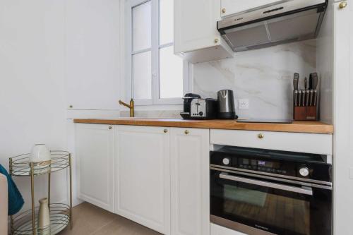 une cuisine avec des armoires blanches et un four à plaques de cuisson dans l'établissement Cosy and chic apartment -1BD-4P- Auteuil, à Paris